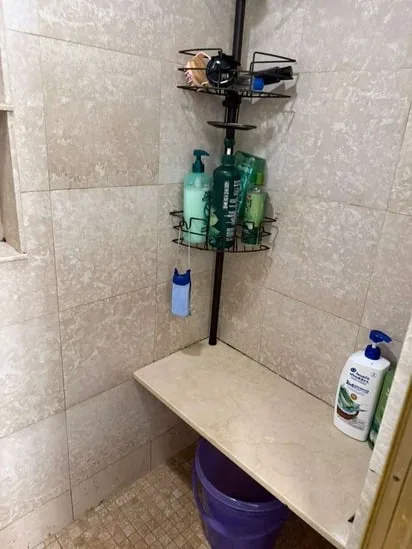 A corner shower area showing deep bathroom tile cleaning results on stone walls and organized shelving.