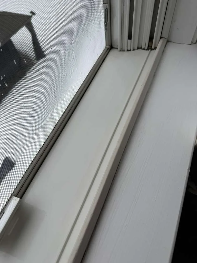A sanitized white window frame and track following a thorough window sill cleaning process.